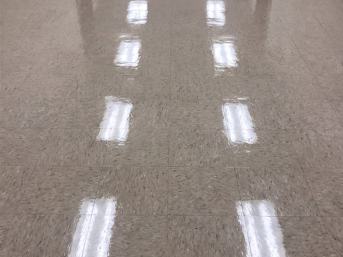 Le même corridor après décapage et cirage : les luminaires se reflètent dans le plancher