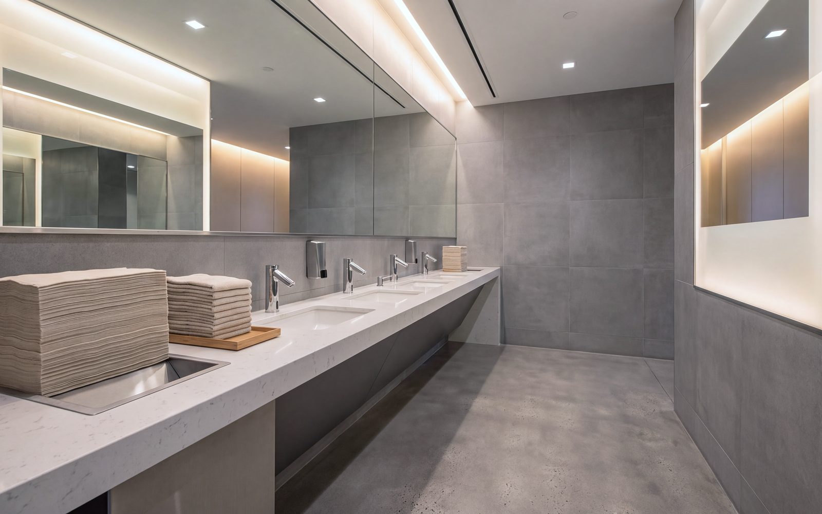 Salle de toilette commerciale entretenue : comptoir, miroirs et plancher de béton poli